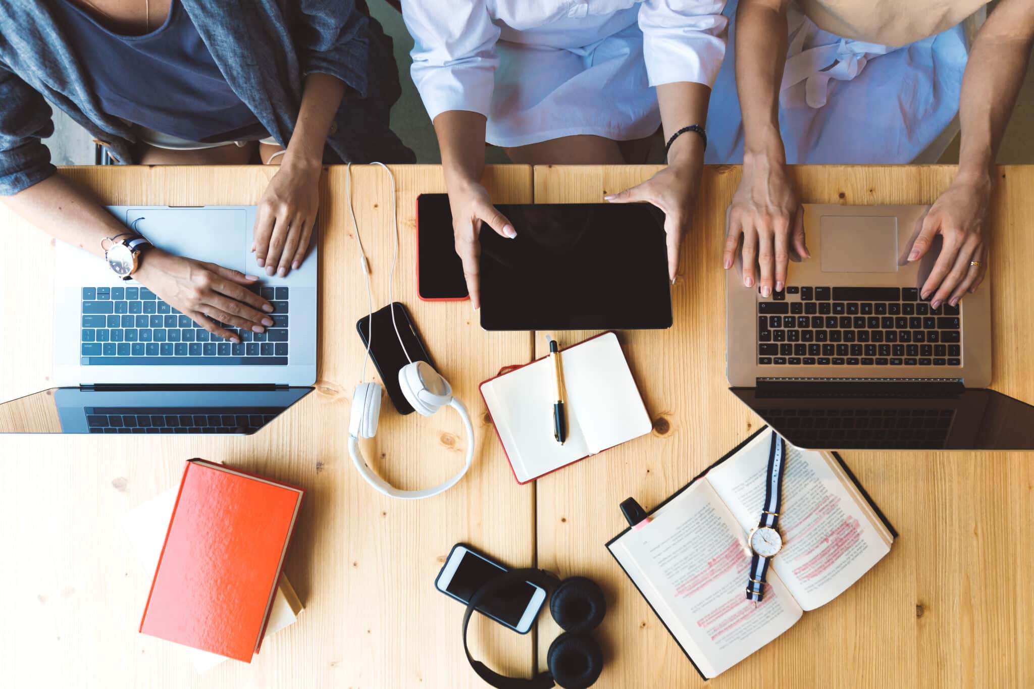 Flat lay picture of three women working with laptops and books sitting at the table together - business woman, co-working and college girls concept